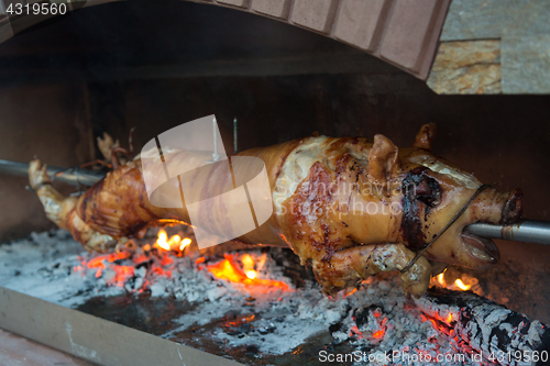 Image of Piglet on a spit over a wood fire.