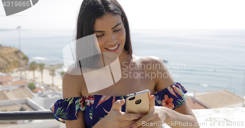 Image of Charming woman using phone on resort