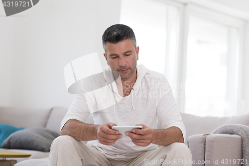 Image of young man using a mobile phone  at home