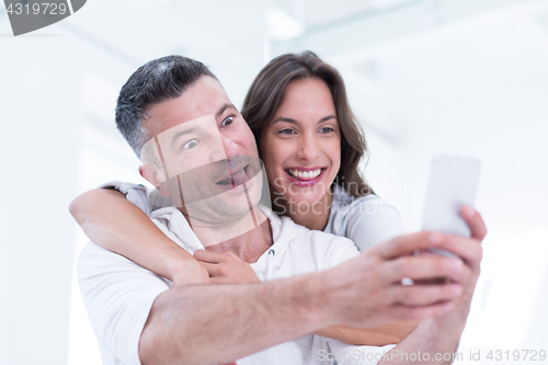 Image of happy couple using mobile phone at home