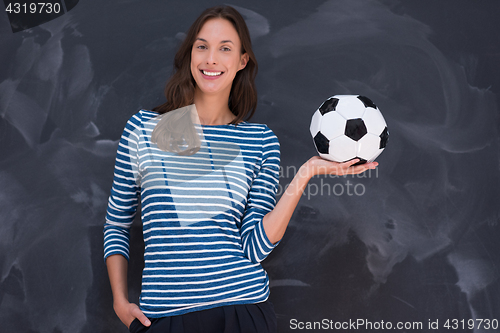 Image of woman holding a soccer ball in front of chalk drawing board