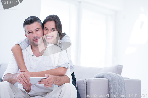 Image of happy couple using mobile phone at home