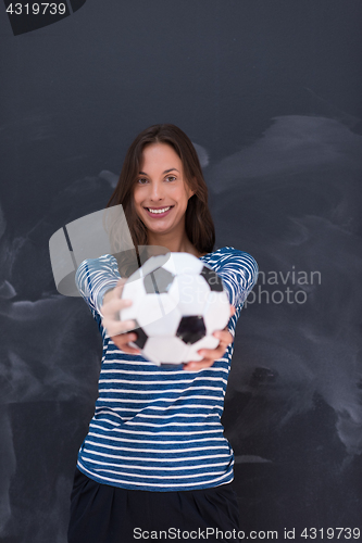 Image of woman holding a soccer ball in front of chalk drawing board