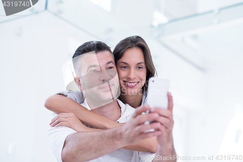 Image of happy couple using mobile phone at home