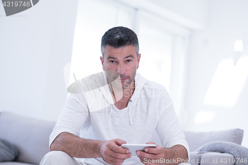 Image of young man using a mobile phone  at home