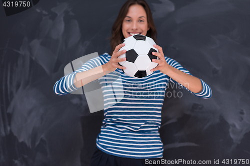 Image of woman holding a soccer ball in front of chalk drawing board