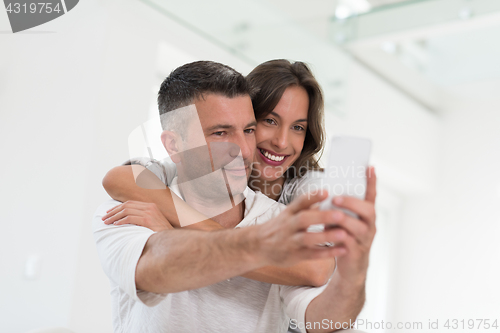 Image of happy couple using mobile phone at home