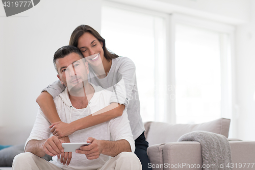 Image of happy couple using mobile phone at home