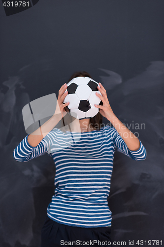 Image of woman holding a soccer ball in front of chalk drawing board