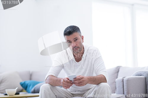 Image of young man using a mobile phone  at home