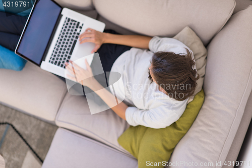 Image of Young woman using laptop at home top view