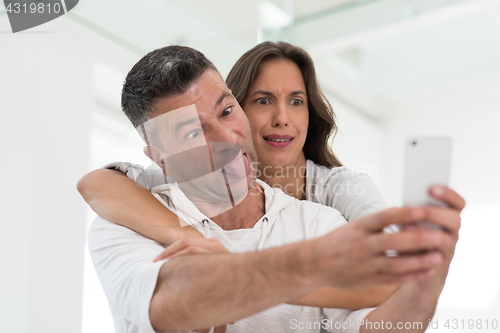 Image of happy couple using mobile phone at home