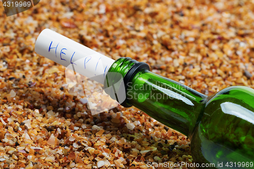 Image of Bottle of wine with help message on sand in beach at sun summer 