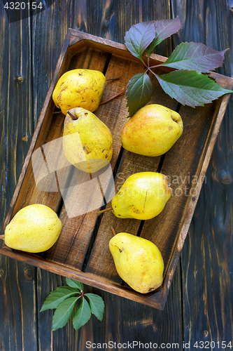 Image of Ripe pear and autumn leaves in wooden box.