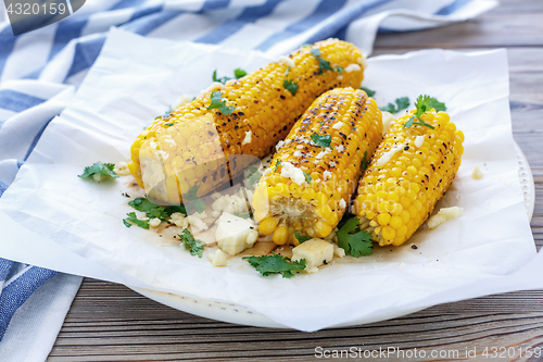 Image of Sweet corn grilled with cheese and cilantro.