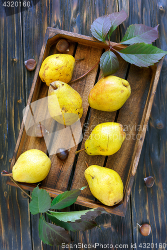 Image of Yellow pears and chestnuts in an old box.