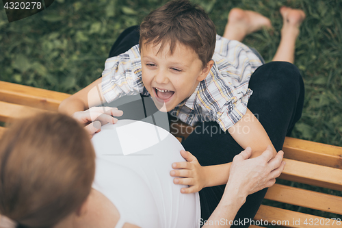 Image of Happy little boy hugging mother in the park at the day time.