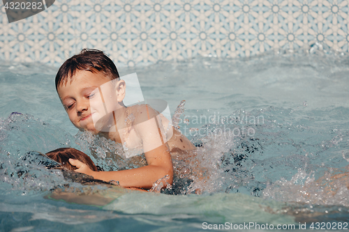 Image of Two happy children playing on the swimming pool at the day time.