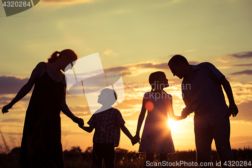 Image of Happy family standing in the park at the sunset time.