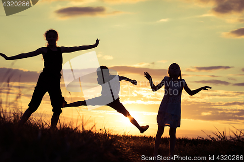 Image of Happy children playing in the park at the sunset time.