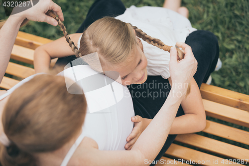 Image of Happy little girl  hugging mother in the park at the day time.