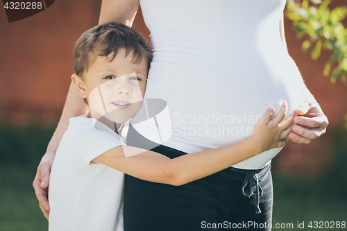 Image of Happy little boy huging mother in the park at the day time.