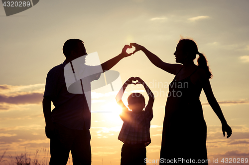 Image of Happy family standing in the park at the sunset time.