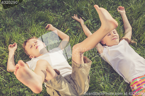 Image of Two happy children playing on the grass at the day time.