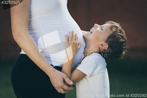 Image of Happy little boy huging mother in the park at the day time.