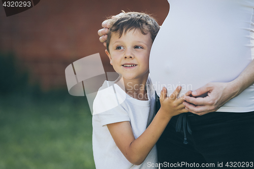 Image of Happy little boy huging mother in the park at the day time.