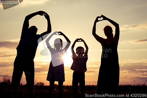 Image of Happy family standing on the field at the sunset time.