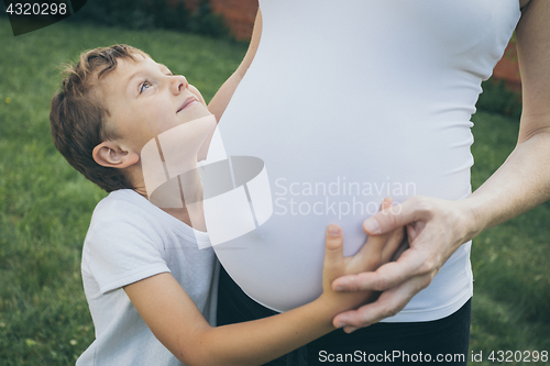 Image of Happy little boy huging mother in the park at the day time.