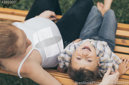 Image of Happy little boy hugging mother in the park at the day time.