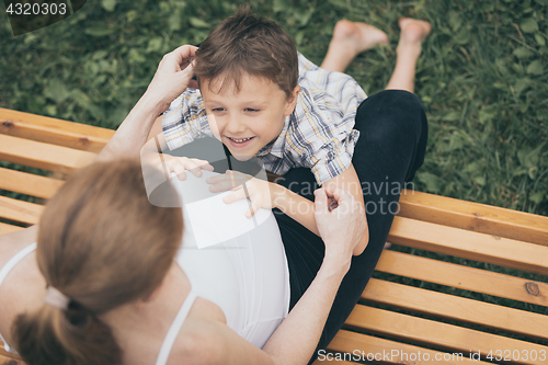 Image of Happy little boy hugging mother in the park at the day time.