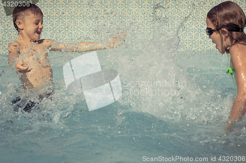 Image of Two happy children playing on the swimming pool at the day time.