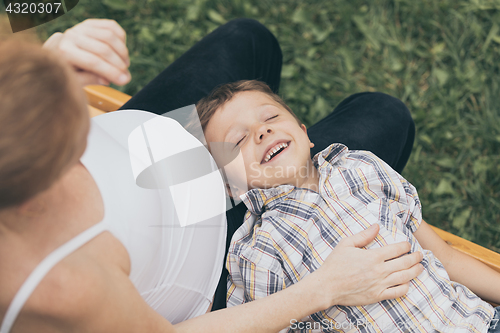 Image of Happy little boy hugging mother in the park at the day time.