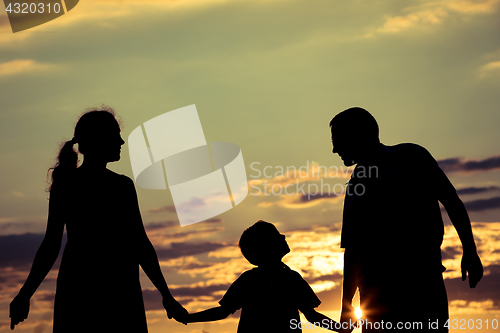 Image of Happy family standing in the park at the sunset time.