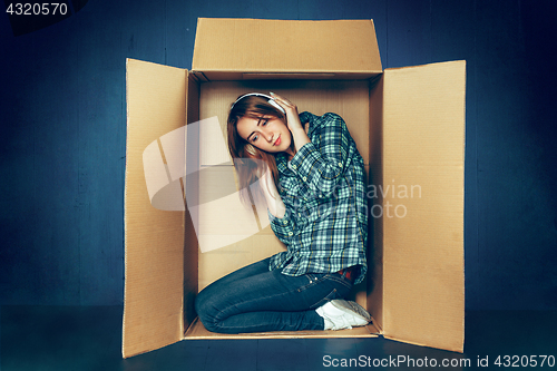 Image of Introvert concept. Woman sitting inside box and working with laptop