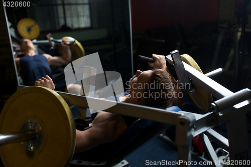 Image of man doing chest press on exercise machine in gym