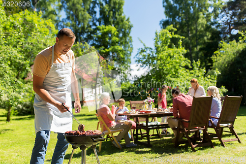 Image of man cooking meat on barbecue grill at summer party