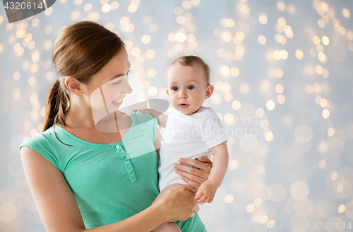 Image of happy young mother with baby over holidays lights