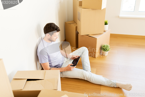 Image of man with tablet pc and boxes moving to new home