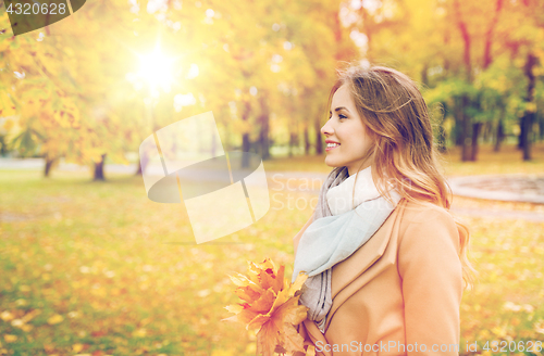 Image of beautiful woman with maple leaves in autumn park