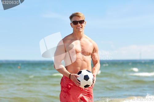 Image of young man with soccer ball on beach