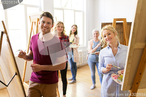 Image of artists with brushes painting at art school