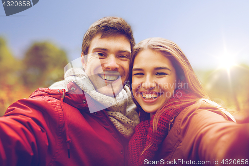Image of happy young couple taking selfie in autumn park