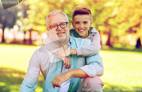 Image of grandfather and grandson hugging at summer park