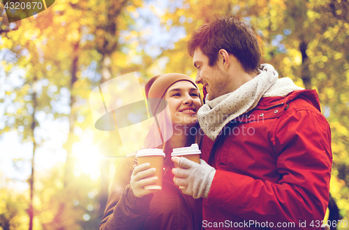 Image of happy couple with coffee walking in autumn park