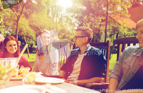 Image of happy friends having dinner at summer garden party