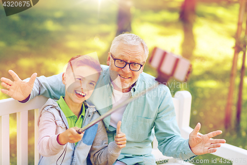 Image of old man and boy taking selfie by smartphone